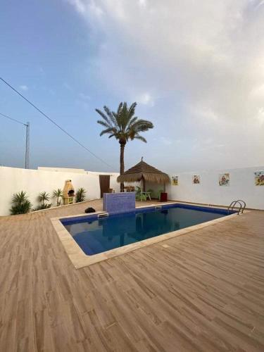 a swimming pool with a palm tree and a building at Drams in Mezraya