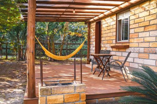a wooden deck with a hammock and a table at Pousada Equilíbrio dos Canyons in Praia Grande