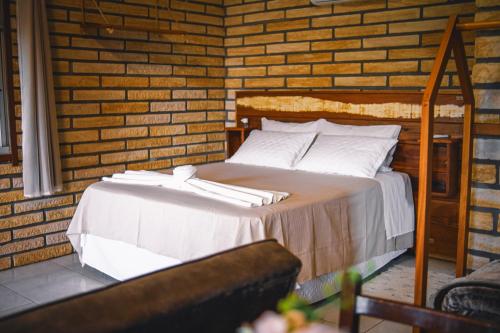 a bed in a room with a brick wall at Pousada Equilíbrio dos Canyons in Praia Grande