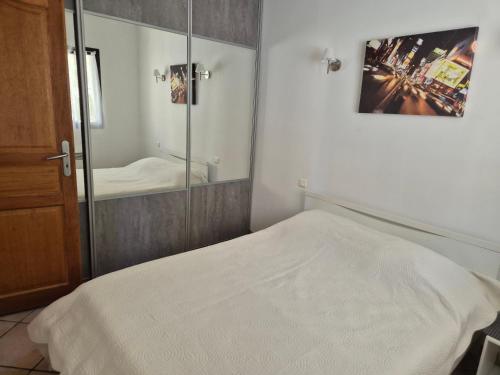 une chambre avec un lit blanc et un miroir dans l'établissement Joli appartement climatisé avec terrasse à moin 10 minutes à pieds de la plage, à Calvi