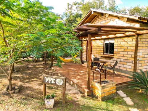 a log cabin with a deck and a sign at Pousada Equilíbrio dos Canyons in Praia Grande
