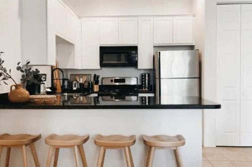 a kitchen with white cabinets and a counter with stools at The Monarch - Chic 1BR Pools and Views in Old Town La Quinta in La Quinta