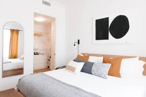 a white bedroom with a large bed and a mirror at The Monarch - Chic 1BR Pools and Views in Old Town La Quinta in La Quinta