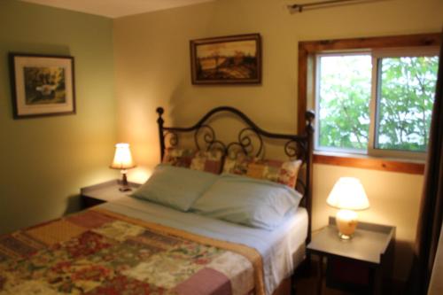 una camera da letto con un letto con due lampade e una finestra di Spry Church Cozy Cottage a Lion's Head