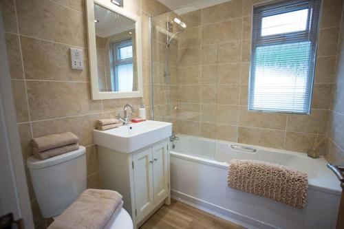 a bathroom with a sink and a tub and a toilet at Cairn Lodge in Coldingham