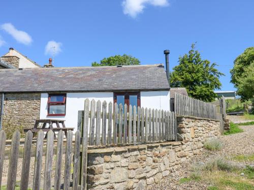 a white house with a fence and a stone wall at Dale View Cottage in Hexham