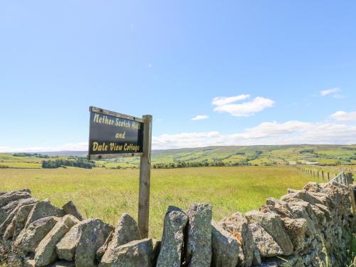 a sign in a field next to a stone wall at Dale View Cottage in Hexham