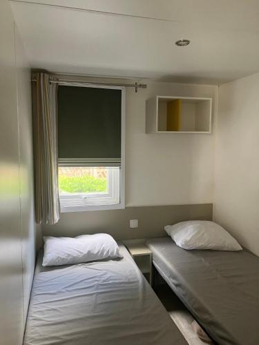 deux lits dans une petite pièce avec une fenêtre dans l'établissement Mobilhome 6 personnes, dans camping 4 étoiles, Argeles sur mer, à Argelès-sur-Mer