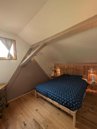 a bedroom with a blue bed in a attic at La grange de la petite souris in Bouxwiller
