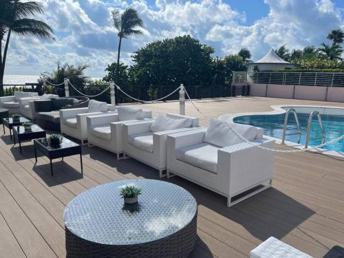 a group of white couches sitting next to a pool at Ocean front 2 Bedroom and 2 Bathroom apartment at The Alexander Resort in Miami Beach