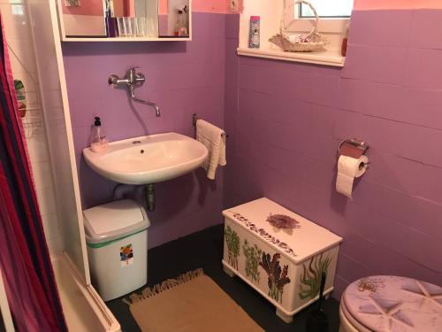 a purple bathroom with a sink and a toilet at Zeleno i plavo in Kraljevica