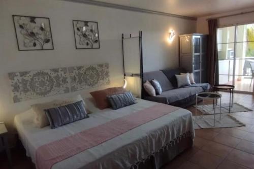 a bedroom with a large bed and a couch at Le Colibri du Paradis in Sainte-Anne