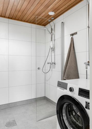 a washing machine in a bathroom with a glass wall at Himos Frame in Jämsä
