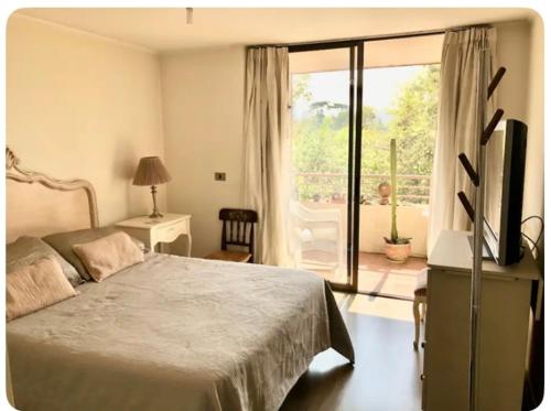 Un dormitorio con una cama y un televisor y un balcón. en Habitación Metro Escuela Militar, en Santiago