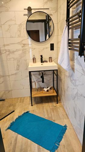 a bathroom with a sink and a mirror and a blue rug at Domki U Sieronia in Mielenko