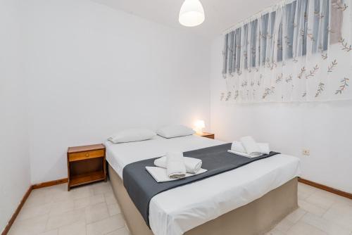 a white bedroom with a large bed with white sheets at Katerina's Garden Mola Kaliva in Mola Kalyva
