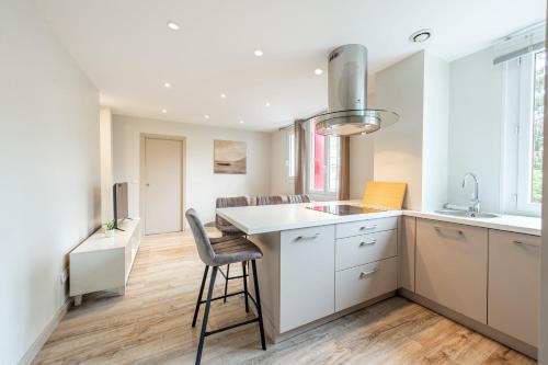 une cuisine avec des placards blancs et un tabouret de bar dans l'établissement RIO Appartement au centre ville, à Annecy
