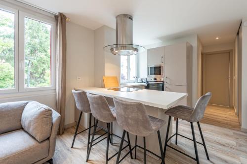 une cuisine avec un comptoir blanc et des tabourets dans l'établissement RIO Appartement au centre ville, à Annecy