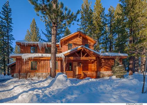 eine Blockhütte im Wald im Schnee in der Unterkunft Caleb Drive 12802 by East West Hospitality in Truckee