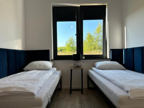 twee bedden in een kamer met twee ramen bij Apartamenty La Venda in Darlowko