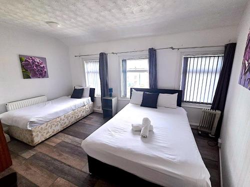 a bedroom with two beds and two windows at Henson hotel in Blackpool