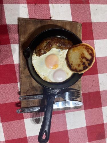 a frying pan with eggs and a sandwich on a table at Hacienda Valencia in Santa Marta