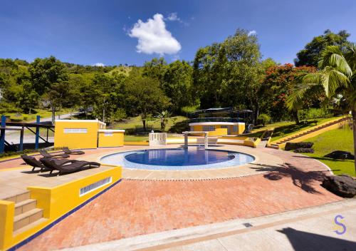 a swimming pool in a yard with two benches at Hotel Sinai SV in Macanal