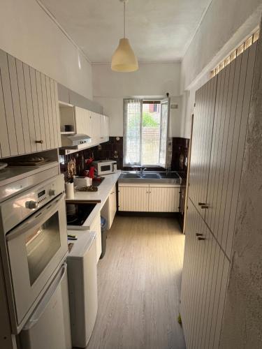 Elle comprend une petite cuisine avec des placards blancs et une fenêtre. dans l'établissement Appartement T3 rez de jardin, à Marseille