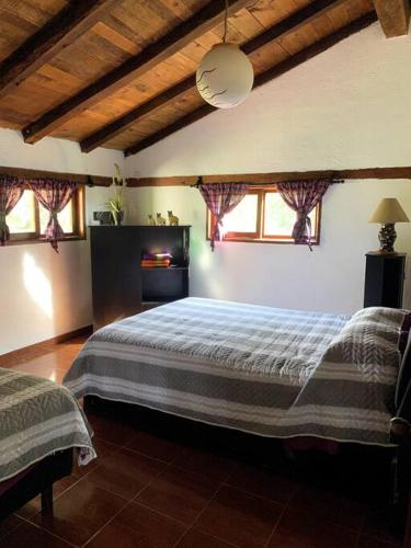 a bedroom with a large bed in a room with windows at Cabaña 1111 in Valle de Bravo