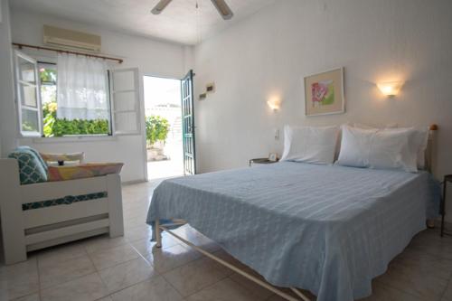 a bedroom with a bed and a chair and a window at Violetta Apartments in Neo Klima