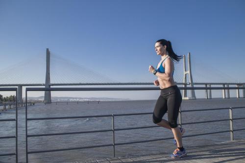 a woman running by the water near a bridge at Oriente Rio Apartments by APT IIN - Parque das Nações in Lisbon