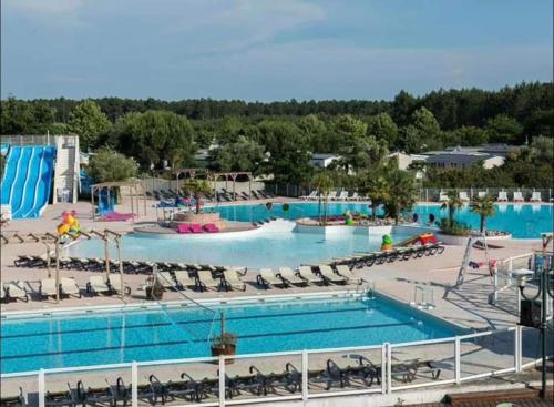 une piscine dans un complexe hôtelier avec chaises et toboggan aquatique dans l'établissement Mobil home camping la réserve Gastes, à Gastes