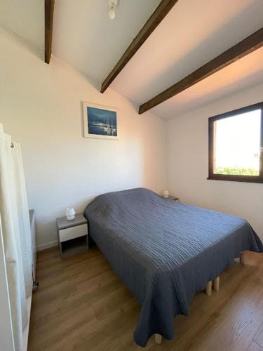 une chambre avec un lit bleu et une fenêtre dans l'établissement Charmante maison à Le Barcarès, au Barcarès