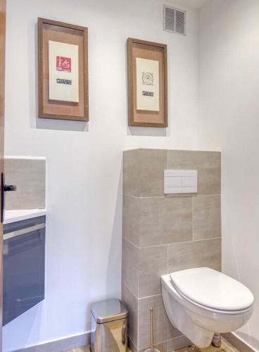 a bathroom with a toilet and two pictures on the wall at Le Lampadaire du Martreuil in Pierrefonds