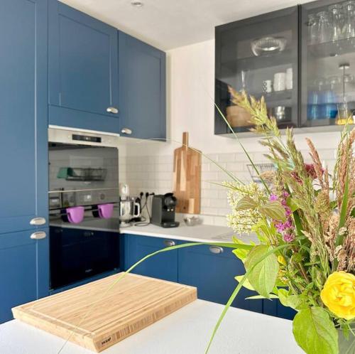 a kitchen with blue cabinets and a vase of flowers at Le Lampadaire du Martreuil in Pierrefonds