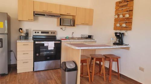 a kitchen with a stove and a counter with stools at Apartamentos Mundo Maya in Flores