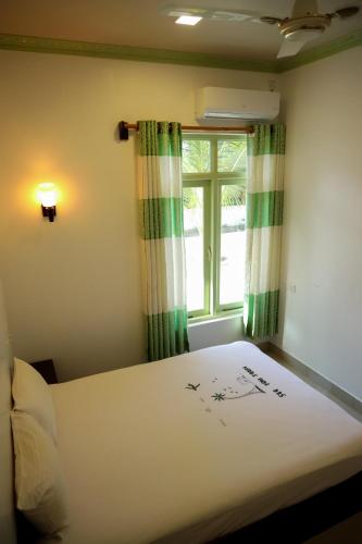 a bedroom with a white bed with a window at Shifa Lodge Maldives in Feridhoo