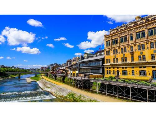 a river with a yellow building next to a bridge at Takatsuki W&M Hotel - Vacation STAY 48542v in Takatsuki