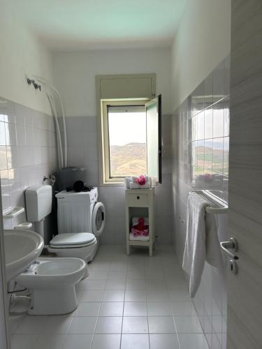 a bathroom with a toilet and a sink and a window at Villa Baglio della Fico a 15 minuti dalla valle dei templi e dal mare in Racalmuto