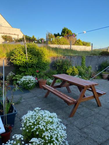a wooden picnic table in a garden with flowers at Babas rooms in Dunvegan