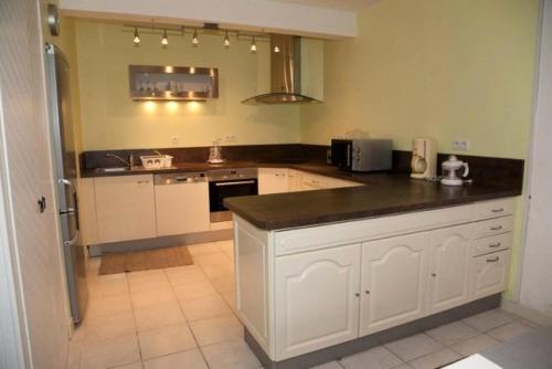 une cuisine avec des armoires blanches et un comptoir noir dans l'établissement Résidence Casino - Charmant T3 en plein cœur de la station balnéaire du Val-André. MAE-5891, à Pléneuf-Val-André