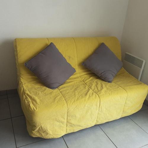 - un canapé jaune avec deux oreillers dans l'établissement Studio les minimes, à La Rochelle