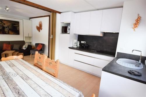 une cuisine avec des armoires blanches et une table dans une pièce dans l'établissement Résidence L'everest - 4 Pièces 8 pers. rénové PLAGNE CENTRE, 3 étoiles MAE-5864, à Aime La Plagne