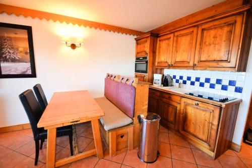 une cuisine avec une table en bois et une petite table et des chaises dans l'établissement Résidence Les Hauts Bois - Résidence de Standing 3 Pièces 6 pers - LES HAUTS BOIS - Piscine, parking MAE-7394, à La Plagne Tarentaise
