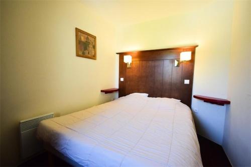 une chambre avec un lit blanc avec une tête de lit en bois dans l'établissement Résidence Le Mont Soleil B - 2 pièces 5 Pers - LE MONT-SOLEIL B - PLAGNE SOLEIL MAE-9354, à Aime La Plagne