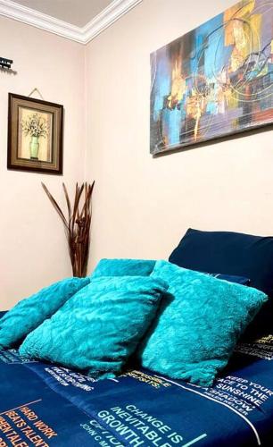a bed with blue sheets and a painting on the wall at SummerPlace Studio Apartments with Kitchenette in Modimolle