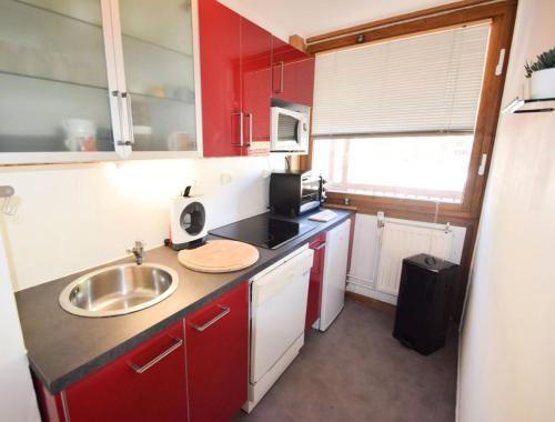 une petite cuisine avec des armoires rouges et un évier dans l'établissement Résidence L'everest - 2 Pièces 5 pers - L'EVEREST - PLAGNE CENTRE MAE-9504, à Aime La Plagne