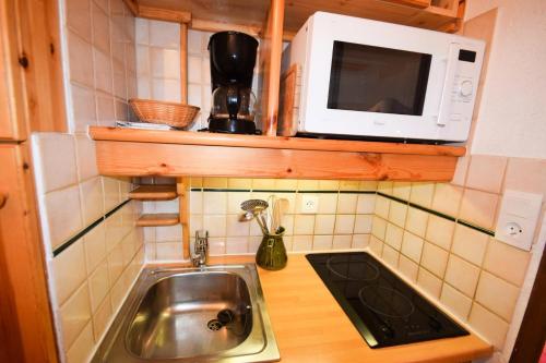 une petite cuisine avec un évier et un micro-ondes dans l'établissement Résidence Le France - Studio 2/3 pers - LE FRANCE - PLAGNE CENTRE MAE-9554, à Aime La Plagne
