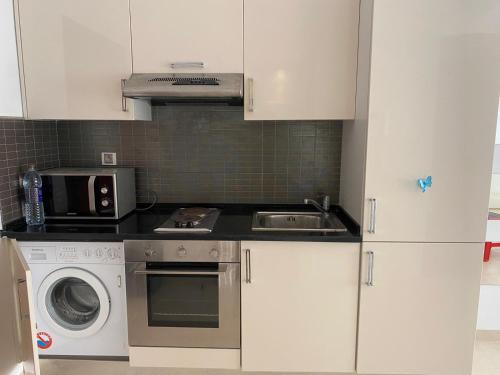 a kitchen with white cabinets and a sink and a microwave at Bel appartement dans une résidence à Folla Aqua Resort Chat Meriem in Sousse