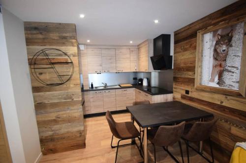 Il comprend une cuisine avec une table et des chaises ainsi qu'un mur en bois. dans l'établissement Résidence Les Arolles - 2 Pièces 4 pers - LES AROLLES - PLAGNE CENTRE - WIFI MAE-7934, à Aime La Plagne